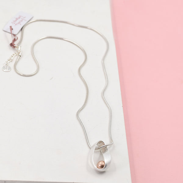 Rose gold bead in oval shaped pendant on long snake chain