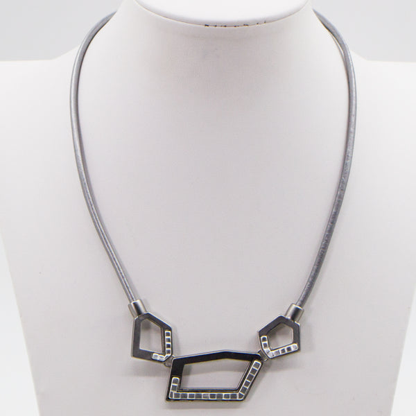 Cutout shapes with metal inlay on short leather necklace