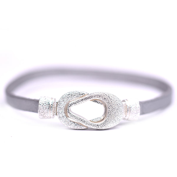 Interlocking rounded shapes in silver on a leather bracelet