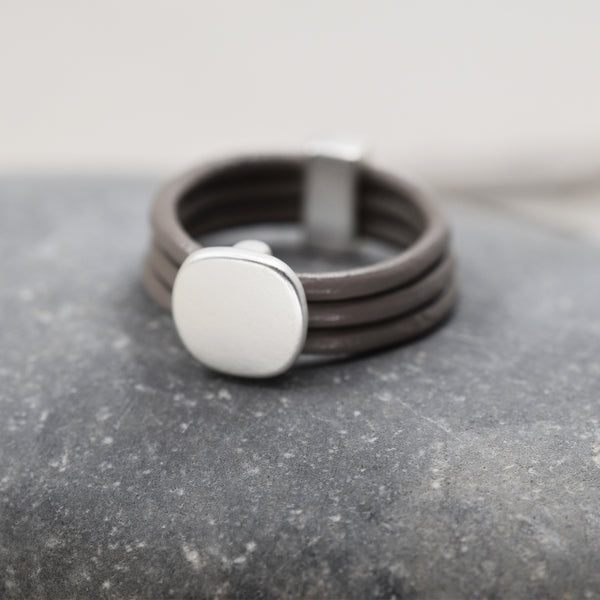 Smooth silver feature on a multi-cord grey leather ring